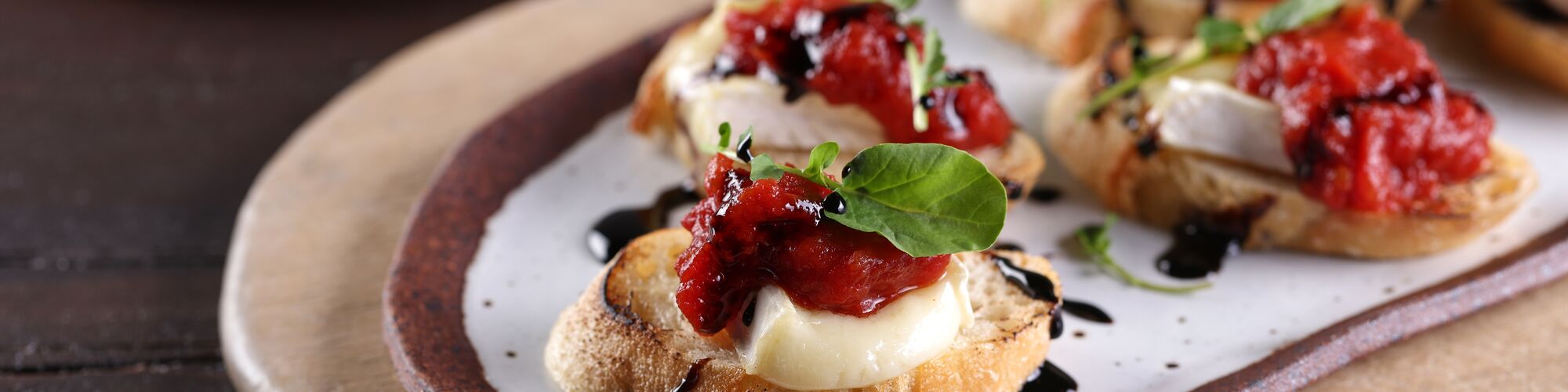 Brie Crostini Topped with Tomato Jam and Balsamic Syrup